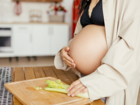 Gravid kvinna i vecka 39 i köket med skärbräda 