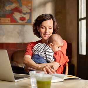 Mamma håller sin baby och kommunicerar med babytecken i hemmiljö