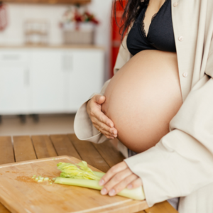 Gravid kvinna i vecka 39 i köket med skärbräda 